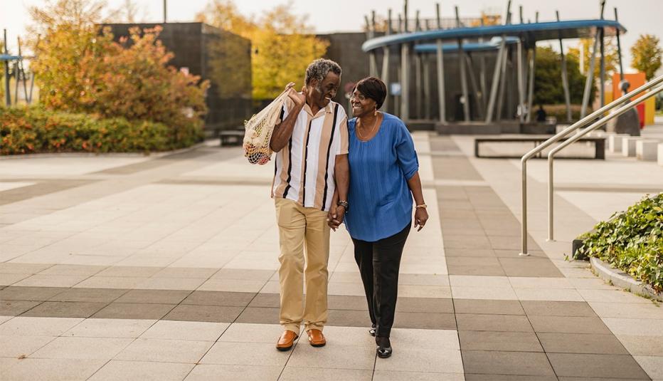 1450577614 A couple holding hands walking together on a concrete walkway